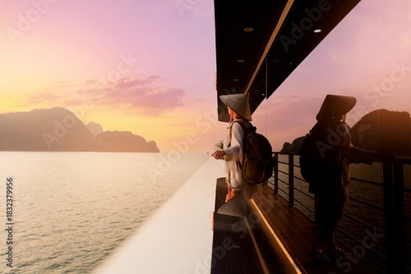 Obraz Scenic view of Halong bay at sunset with female in traditional hat