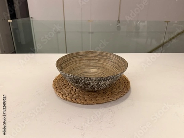 Obraz Woven Home Decor: Handmade natural fiber bowl and placemat arranged on a sleek white countertop in a minimalist modern kitchen.