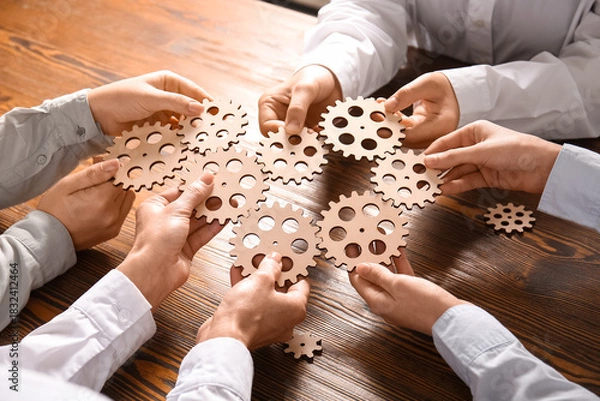 Obraz Group of business people holding wooden gears at table