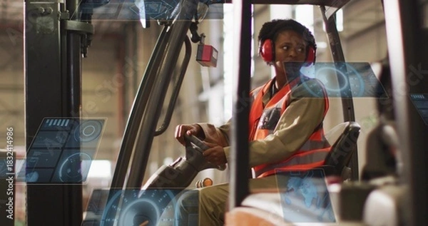 Obraz Operating forklift, woman wearing orange vest and red earmuffs steering in warehouse, holograms