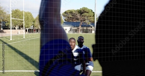 Fototapeta Reacting kneeling player looking at camera on rugby pitch, silhouette blocking, wearing striped kit
