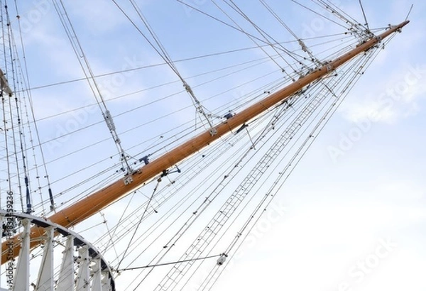 Fototapeta Close-up of a ship's mast and rigging against a partly cloudy sky