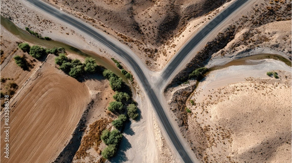 Obraz Intersecting Paths: A bird's-eye view reveals a road intersection cutting across a vast landscape, symbolizing choices, journeys, and destinations. The roads.