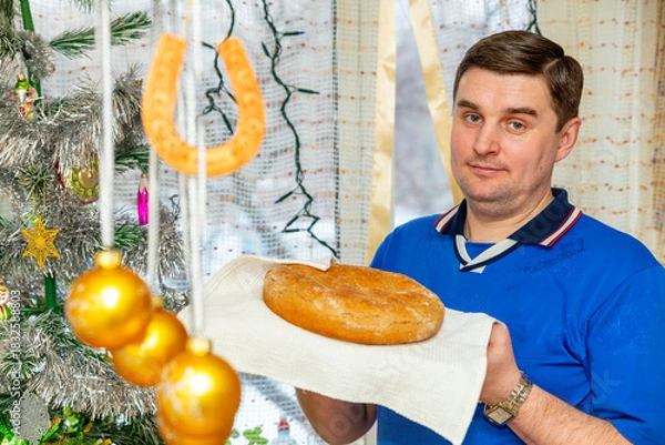 Fototapeta handsome young man holding freshly baked bread in his hands for New Year's holiday