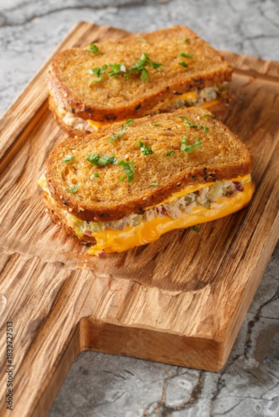 Obraz Breakfast Tuna Melt sandwich made of rye bread, canned tuna and melted cheese close-up on a wooden board on the table. Vertical