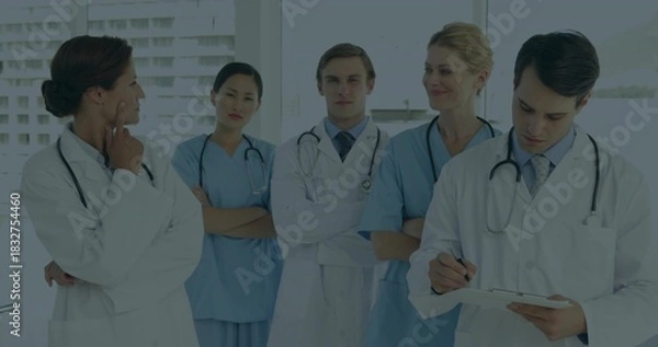 Obraz Standing five staff wearing lab coats and scrubs near windows, holding clipboard and stethoscopes