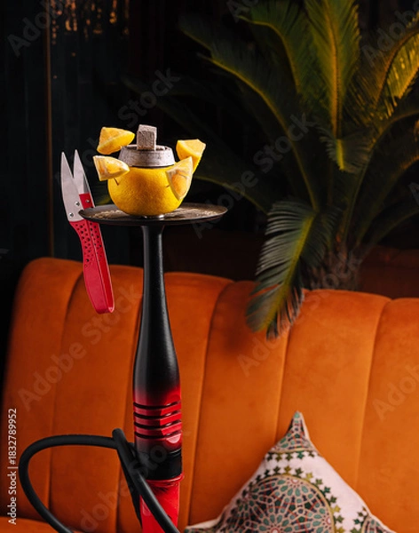 Fototapeta Hookah with lemon and scissors placed on an orange sofa in a cozy lounge