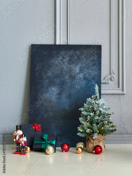 Obraz Cozy Christmas interior scene with decorated mini tree, ornaments, gifts, nutcrackers, modern chair, and elegant textured wall background.