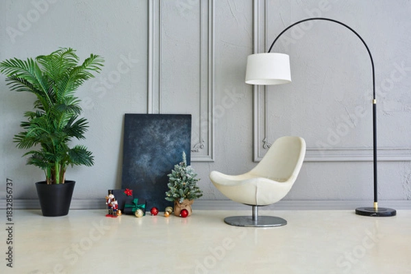 Obraz Cozy Christmas interior scene with decorated mini tree, ornaments, gifts, nutcrackers, modern chair, and elegant textured wall background.