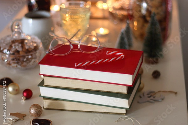 Fototapeta Cookie jar, tea, wine, nuts, books, lit candles and Christmas decorations on the table. Cozy Christmas hygge at home. Selective focus.