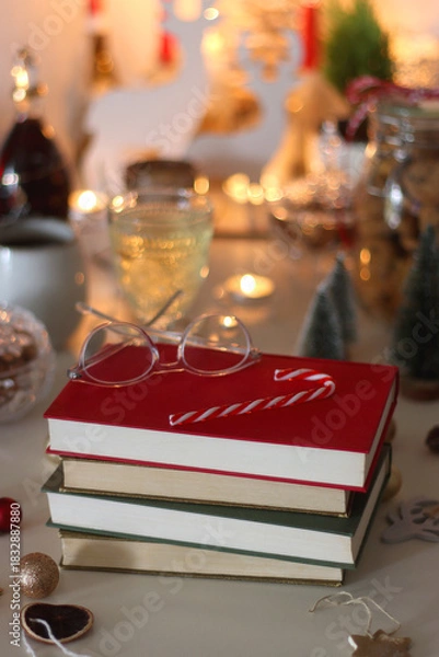 Fototapeta Cookie jar, tea, wine, nuts, books, lit candles and Christmas decorations on the table. Cozy Christmas hygge at home. Selective focus.