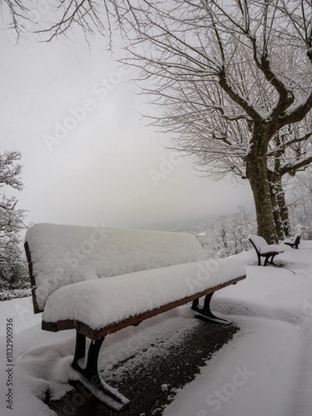 Fototapeta Empty snow covered park bench symbolizing waiting, solitude, or rest