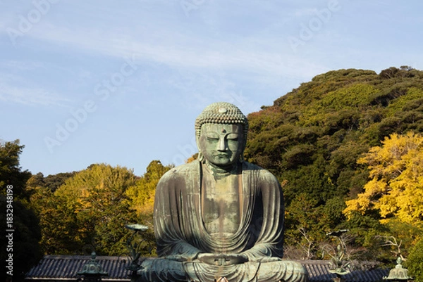 Fototapeta Great Buddha of Kamakura against a clear blue sky, capturing the serene expression of the iconic Daibutsu statue
