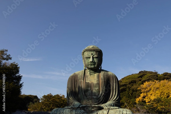 Fototapeta Great Buddha of Kamakura against a clear blue sky, capturing the serene expression of the iconic Daibutsu statue
