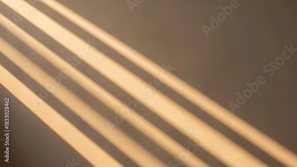 Fototapeta Sunlight stripes casting shadows on a beige wall, creating a serene and warm atmosphere.