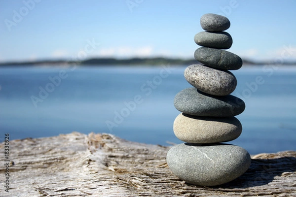 Fototapeta Smooth stones balancing on log