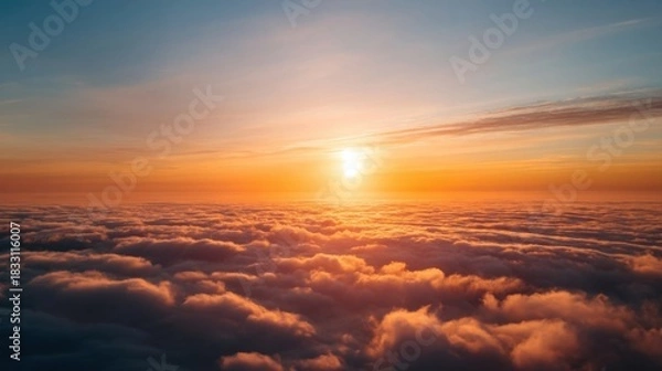 Obraz A stunning sunset over fluffy clouds with a radiant sun glowing at the center, painting the sky in warm hues.