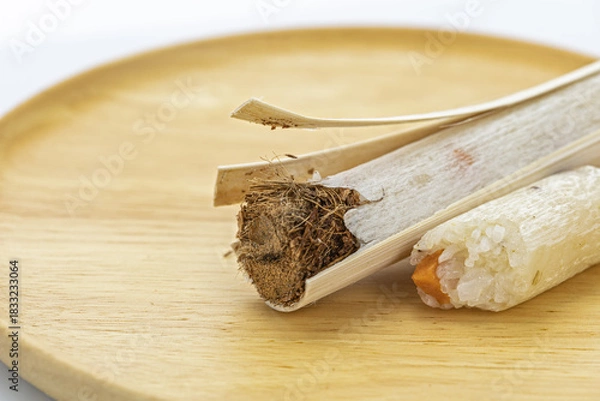 Obraz Close-up of Thai traditional glutinous rice with savory yam wrapped inside a bamboo stick, partially peeled open to reveal
