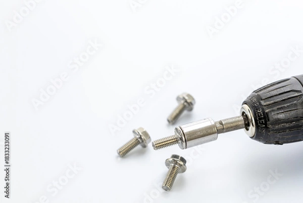 Obraz Close-up of a black grip release screwdriver with hex socket bit and four silver metal screws on white background