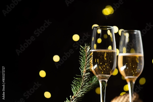 Fototapeta Festive champagne glasses on a dark background with bokeh garland, copy space