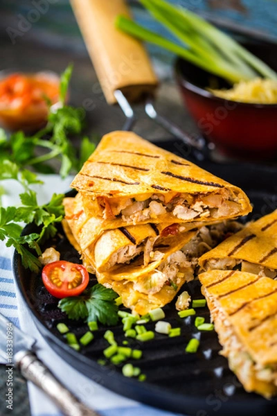 Fototapeta Mexican food quesadilla with grilled chicken, salsa and cheese, with greens and vegetables