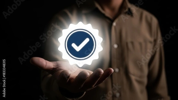 Obraz Man holding glowing verified badge with checkmark symbol in his palm against dark background
