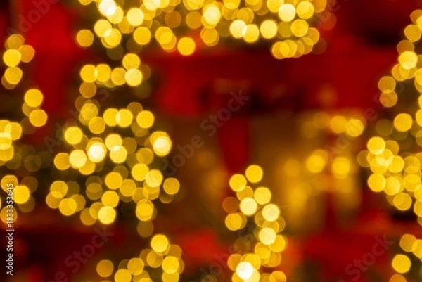 Fototapeta A glowing holiday-themed background featuring soft, golden bokeh lights against rich red tones, creating a warm and festive ambiance