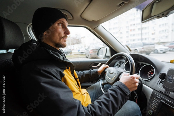 Fototapeta focused driver navigating, concentrated driver maintaining safety in bustling city environment, individual behind steering wheel exhibiting composure during busy city commute