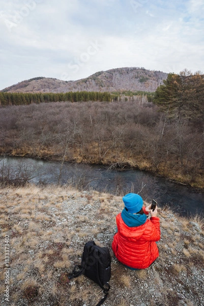 Fototapeta Nature photographer capturing scenery, Explorer documenting river bend and hillside with camera equipment, Creative outdoor photographer capturing reflective water and mountain scenery
