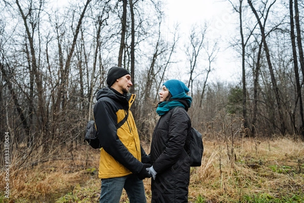 Fototapeta partners sharing serene moment, couple united amid wintery woodland tranquility, two individuals bonding peacefully in open clearing surrounded by dormant trees and muted sky