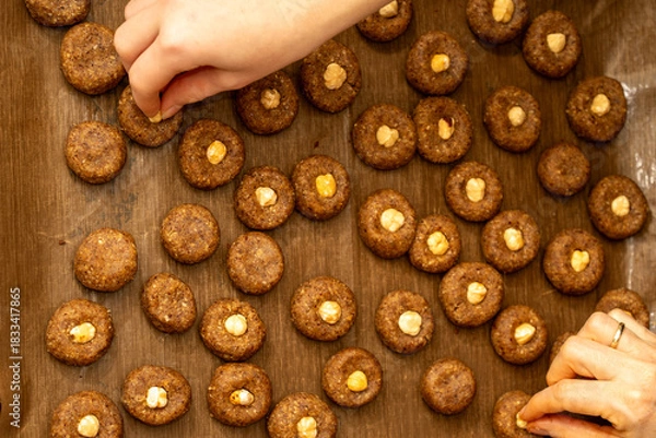 Fototapeta Top view of woman and child placing hazelnuts on cookies together. Family holiday tradition and teamwork
