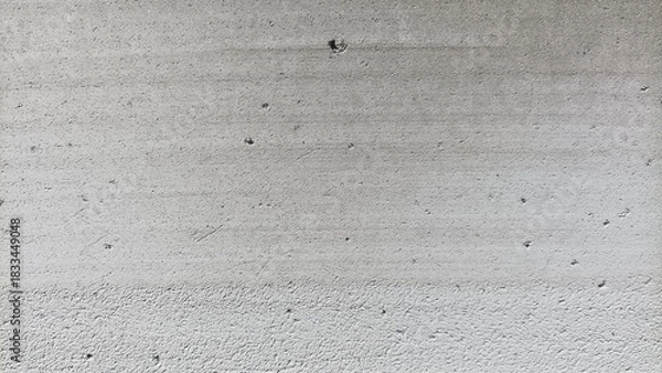 Fototapeta Texture of a rough gray cement wall surface with small holes and subtle patterns, ideal for backgrounds, construction themes, and industrial design.