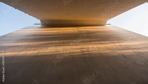 Fototapeta Looking Up From Underneath A Concrete Bridge With Golden Sunlight Casting Long Shadows On A Clear Day