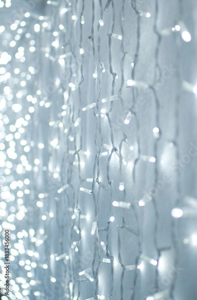 Obraz  Background of Glowing Christmas lights on a white surface. Vertical photo.
