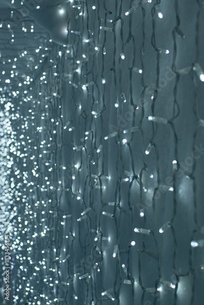 Obraz  Background of Glowing Christmas lights on a white surface. Vertical photo.