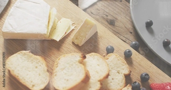 Fototapeta Displaying brie wedge resting on wood cutting board, with toasted crostini and loose blueberries