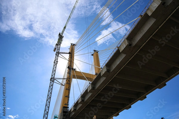 Obraz Cable-Stayed Bridge Construction with Tower Crane Under Blue Sky