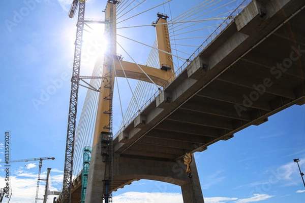Obraz Cable-Stayed Bridge Construction with Tower Crane Under Blue Sky