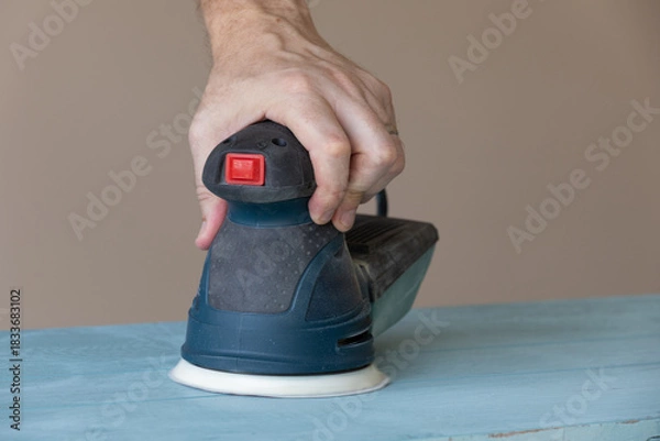 Fototapeta Woodworker Removing Paint With Power Sander