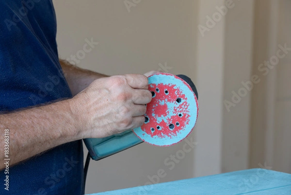 Fototapeta Man taking sanding disk off of orbital sander