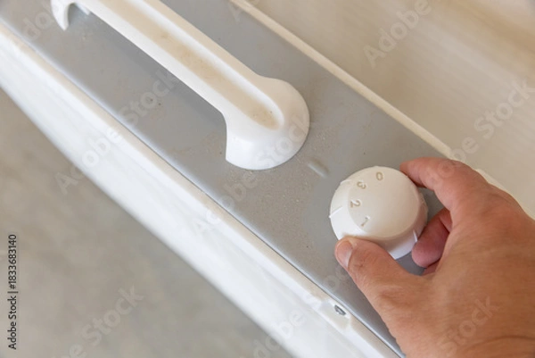 Fototapeta Hand turning dial on box fan