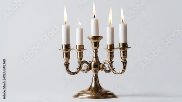 Fototapeta A brass candelabra with five lit white candles stands against a plain background.