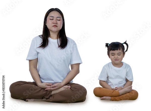 Fototapeta Mother teaching her young daughter to meditate, sitting peacefully in a cross-legged pose  isolated on white with clipping path.