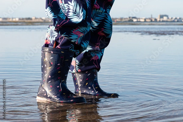 Fototapeta Enfant marchant en bottes dans l'eau ) marée basse