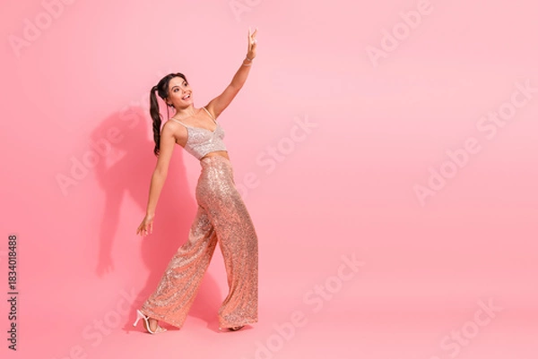 Obraz Glamorous young woman in a pink sequin outfit dancing against a pink background for fashion lifestyle and party advertising