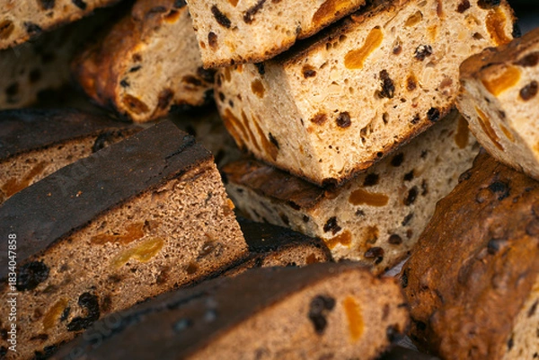 Obraz Close-up of freshly cut fruit bread slices with visible dried fruits and nuts, highlighting their texture and golden-brown crust.
