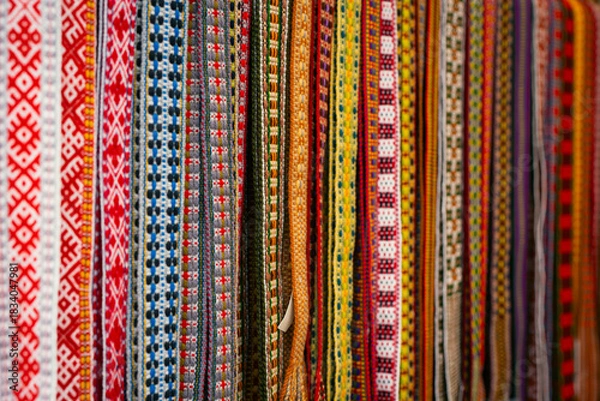 Obraz Close-up of colorful handwoven traditional belts displayed in a basket, highlighting their intricate patterns and vibrant colors.