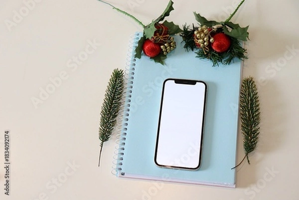 Obraz Smartphone with blank screen on notebook with christmas decoration. Social media mock up. 