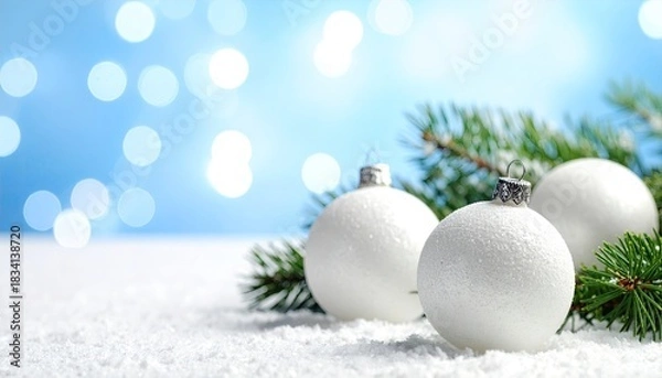 Fototapeta Elegant white Christmas ornaments nestled in fresh snow with festive blue bokeh lights.