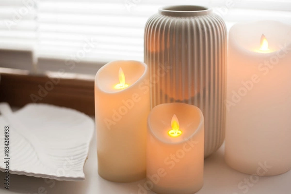 Obraz Led battery candles, tray and vase over white background with soft window light.